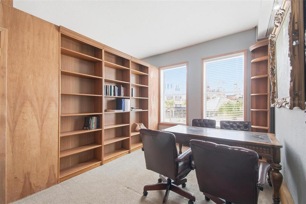 A home office features built-in wooden bookshelves, a desk with two leather chairs, and two windows — 101 PALM HARBOR PARKWAY UNIT OB2, PALM COAST, FL