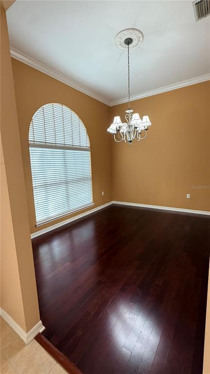A dining room features dark hardwood floors, tan walls, and an arched window with blinds — 2782 HIGH RIDGE DRIVE, LAKELAND, FL