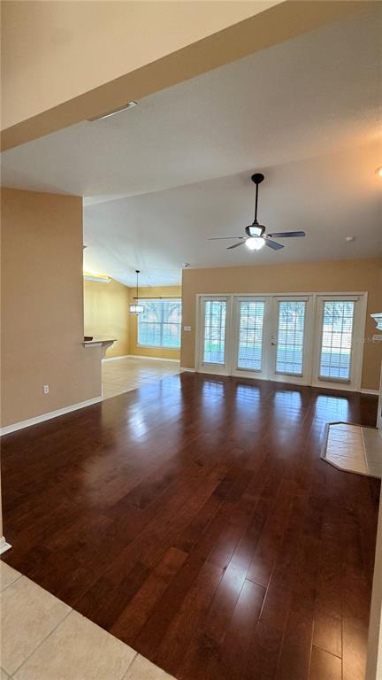 A spacious living room features dark hardwood floors, a ceiling fan, and large glass doors — 2782 HIGH RIDGE DRIVE, LAKELAND, FL