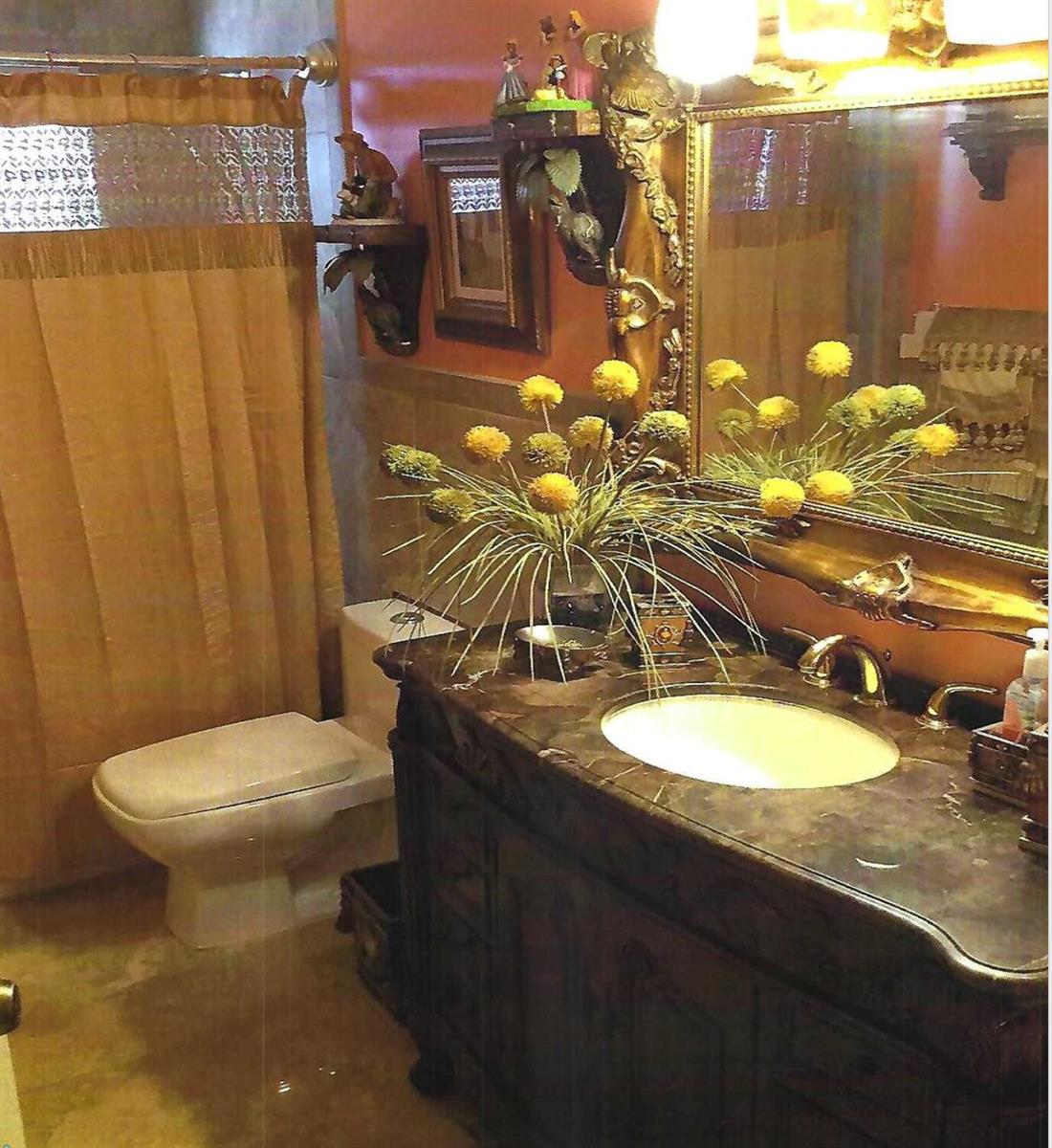 A bathroom features a dark wood vanity with a marble countertop, gold-toned mirror, and shower curtain — 8862 Jaspers Drive, Boynton Beach FL 33472, BOYNTON BEACH, FL