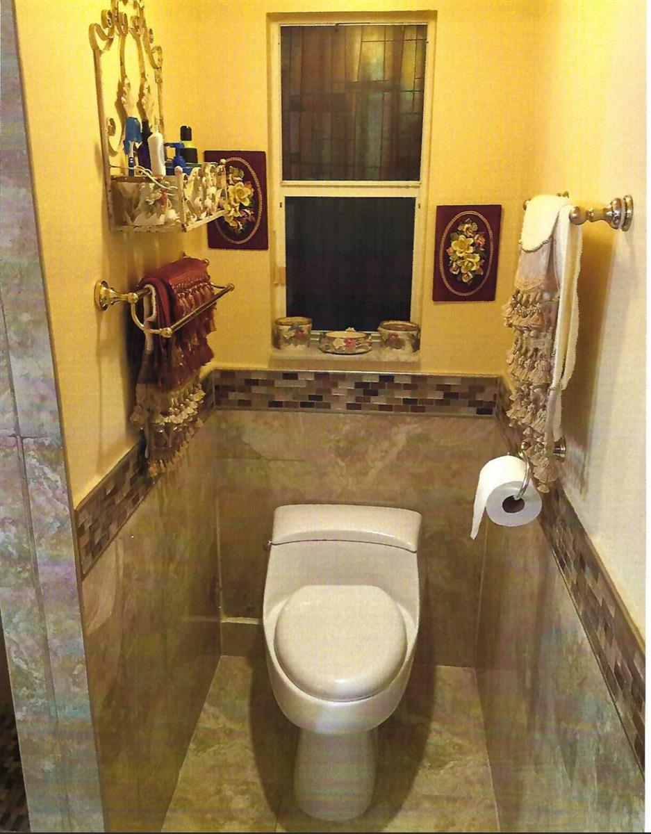 A small bathroom features a toilet, tiled walls, a window, and decorative wall hangings — 8862 Jaspers Drive, Boynton Beach FL 33472, BOYNTON BEACH, FL