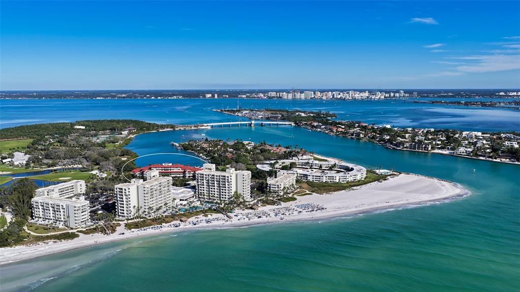 An aerial view shows beachfront high-rise buildings and a resort complex along a coastal bay — 225 SANDS POINT ROAD UNIT 6201, LONGBOAT KEY, FL