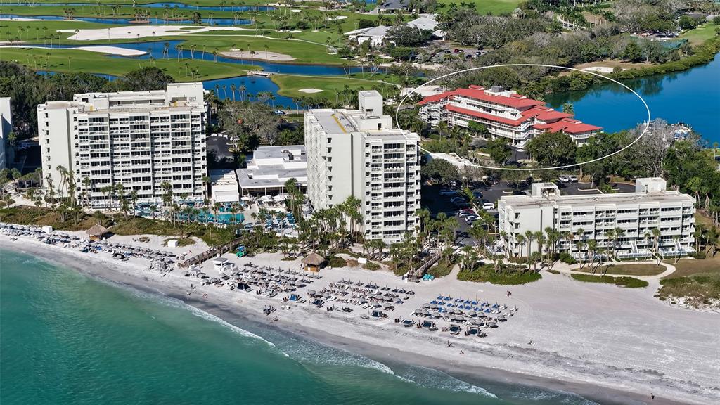An aerial view shows a beachfront resort complex with multiple buildings and a swimming pool — 225 SANDS POINT ROAD UNIT 6201, LONGBOAT KEY, FL