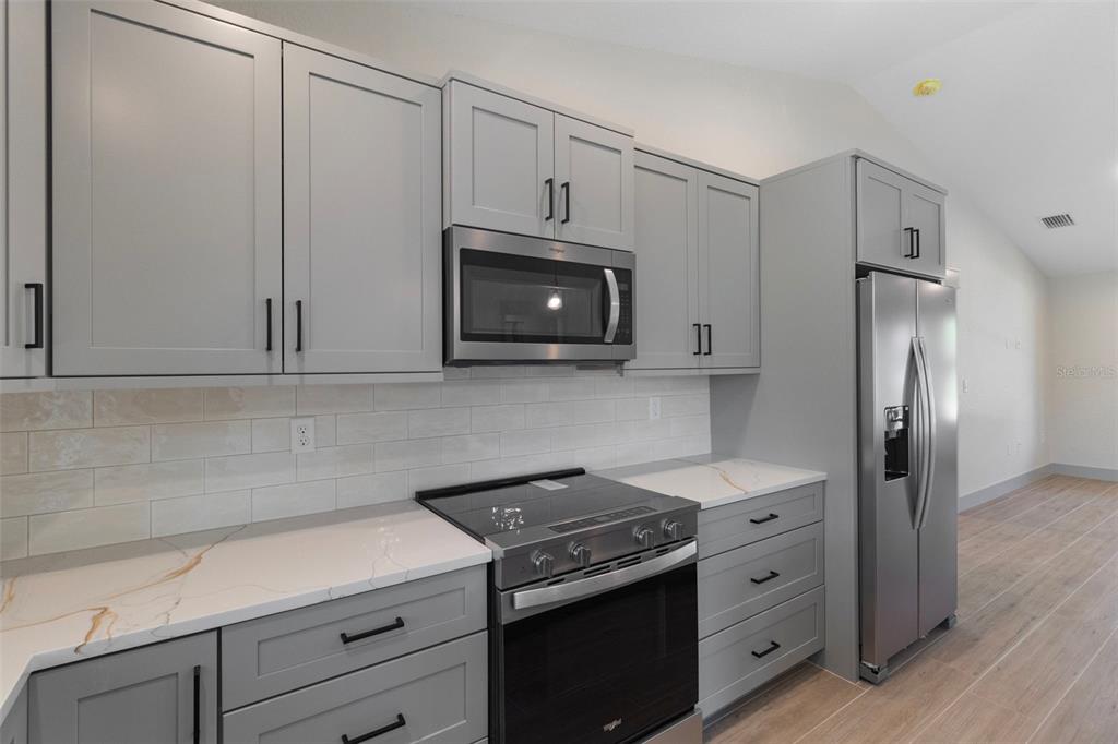 A kitchen features gray shaker cabinets, stainless steel appliances, and white marble-look countertops — 4125 JOSEPH STREET, PORT CHARLOTTE, FL