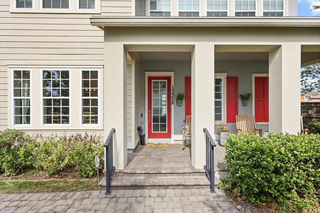 A front porch with a red door, stone steps, and two wooden rocking chairs — 13358 BEEBE ALLEY, ORLANDO, FL