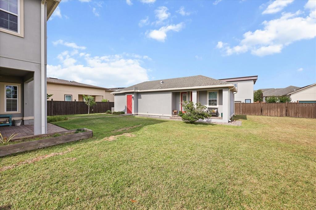 A backyard view of a gray house with a red door and a wooden fence — 13358 BEEBE ALLEY, ORLANDO, FL