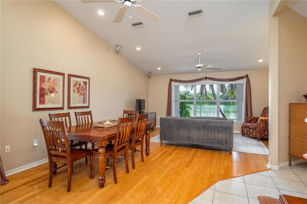 A dining area with hardwood floors opens into a living room overlooking a lake — 5667 WATER OAK LANE, MULBERRY, FL
