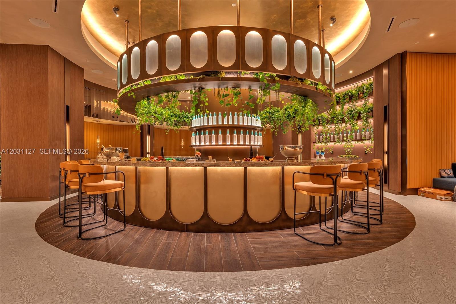 A circular bar features gold-toned paneling, hanging greenery, and modern stools on a wood floor — 20 NE 11th St # 3106B, Miami FL 33132, MIAMI, FL