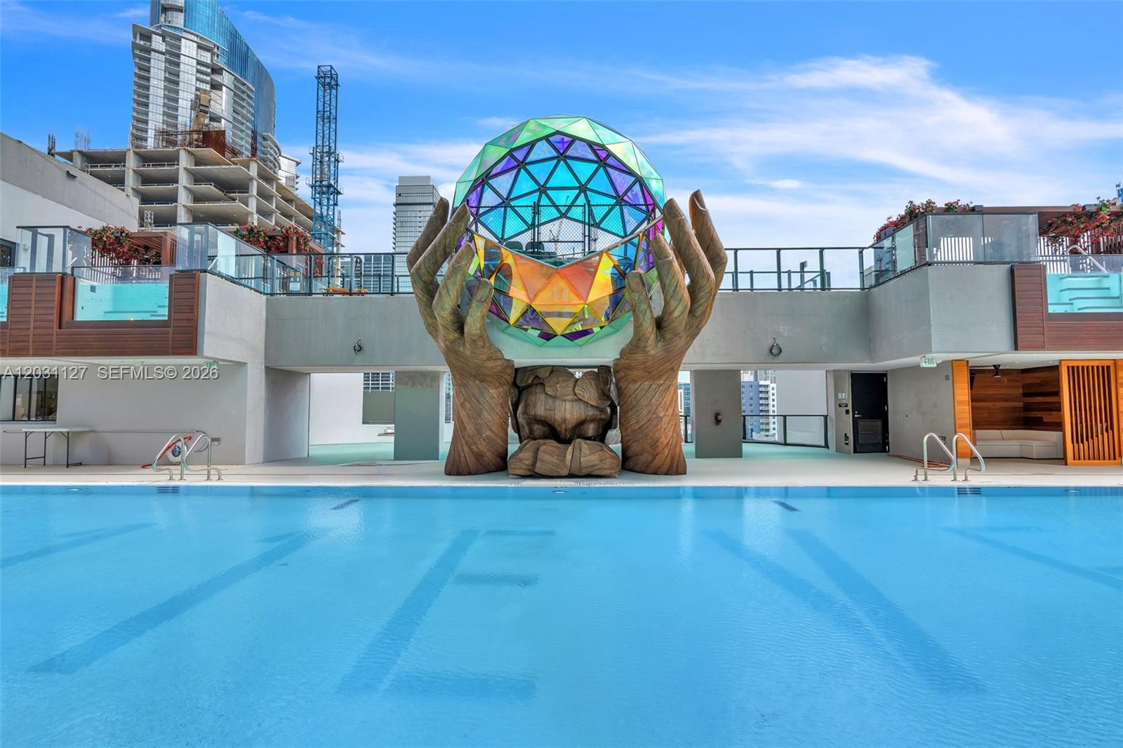 A swimming pool features a large sculpture of hands holding a geometric, iridescent glass sphere — 20 NE 11th St # 3106B, Miami FL 33132, MIAMI, FL