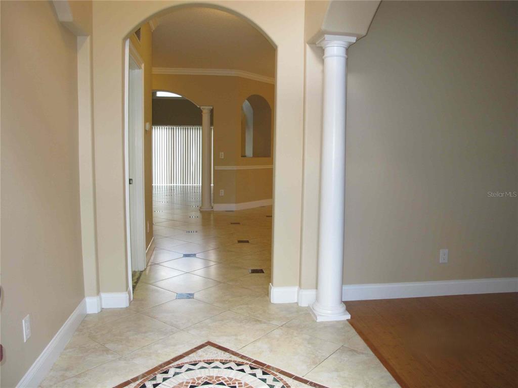 A tiled entryway leads through an arched opening toward a living area with white columns — 6828 LUCCA STREET, ORLANDO, FL