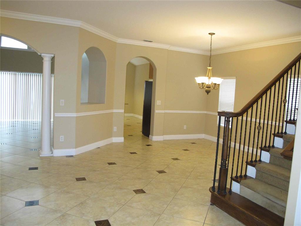 An interior view of a foyer featuring tile flooring, a staircase, and arched doorways — 6828 LUCCA STREET, ORLANDO, FL
