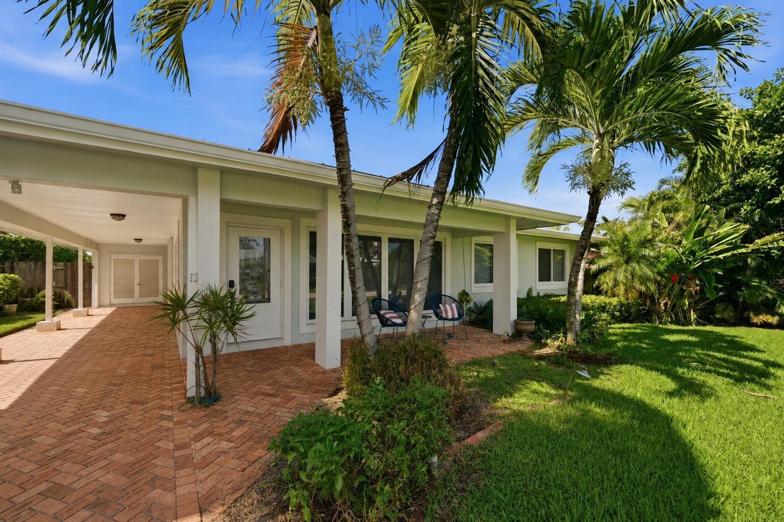 A brick patio with palm trees sits in front of a house with a carport — 2685 SE 6th Street, Pompano Beach FL 33062, POMPANO BEACH, FL