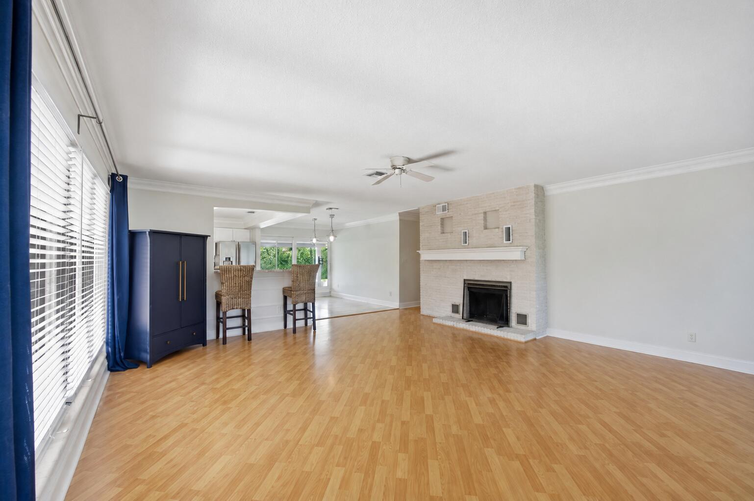 A living room with light wood floors, a brick fireplace, and a blue storage cabinet — 2685 SE 6th Street, Pompano Beach FL 33062, POMPANO BEACH, FL