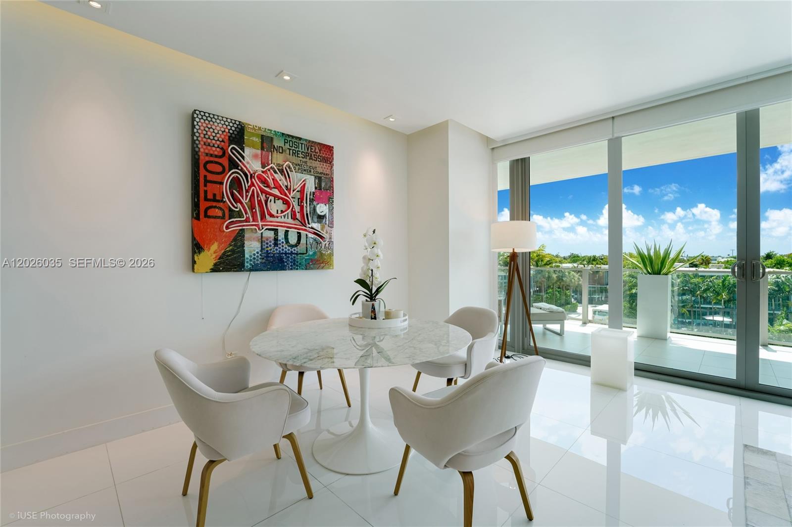 A dining area with a marble table, four chairs, graffiti art, and a balcony view — 350 Ocean Dr # 405N, Key Biscayne FL 33149, KEY BISCAYNE, FL