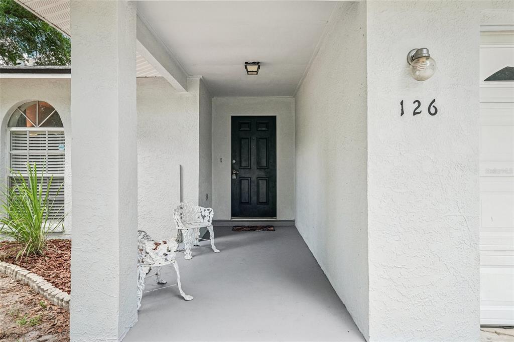 A covered front porch features a dark door, two white chairs, and house number 126 — 126 S SAINT CLOUD AVENUE, VALRICO, FL