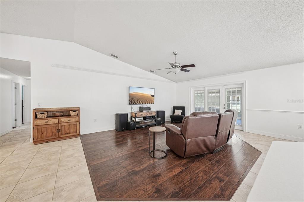 A living room features a vaulted ceiling, dark wood flooring, and a wall-mounted television — 126 S SAINT CLOUD AVENUE, VALRICO, FL