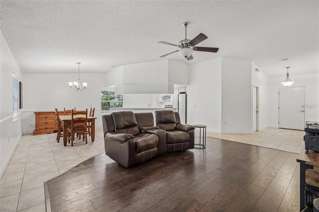 A living room with dark wood flooring, a brown leather sofa, and an adjacent dining area — 126 S SAINT CLOUD AVENUE, VALRICO, FL