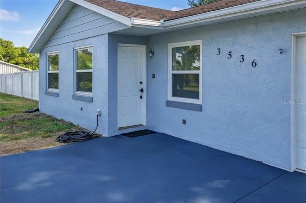 The exterior of a light blue house features a painted concrete patio and white door — 3536 EAGLES NEST ROAD, FRUITLAND PARK, FL
