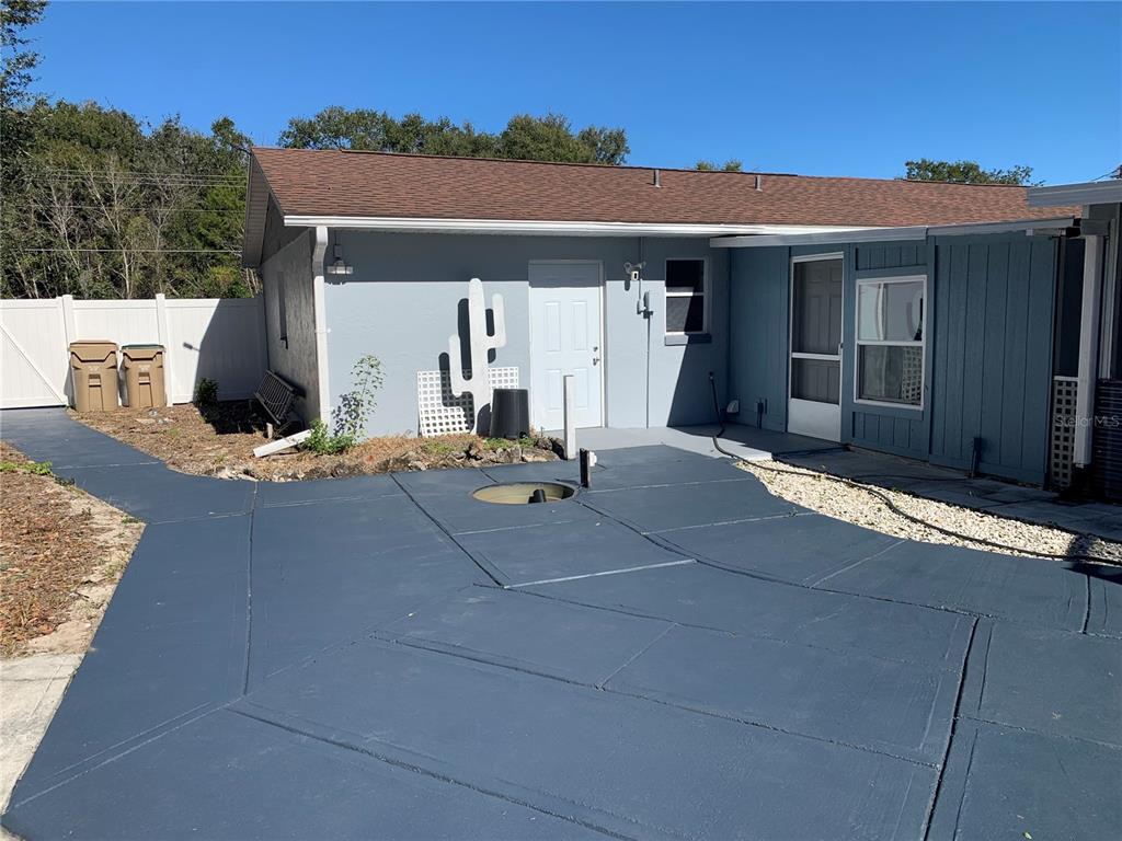 A gray house exterior features a painted patio, a white door, and a white fence — 3536 EAGLES NEST ROAD, FRUITLAND PARK, FL