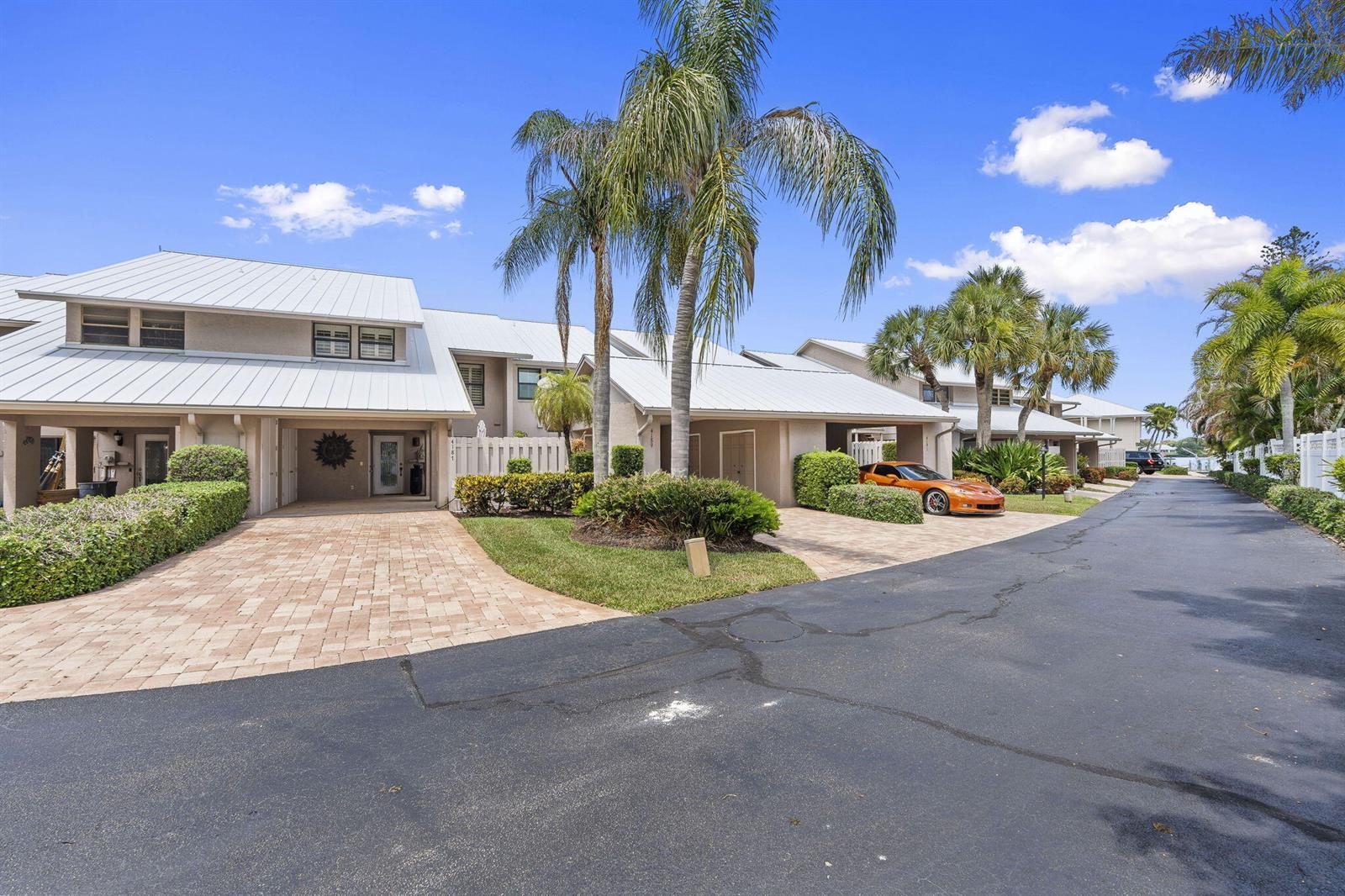 A row of townhouses with metal roofs, paved driveways, and palm trees under a blue sky — 4189 SE Saint Lucie Boulevard, Stuart FL 34997, STUART, FL