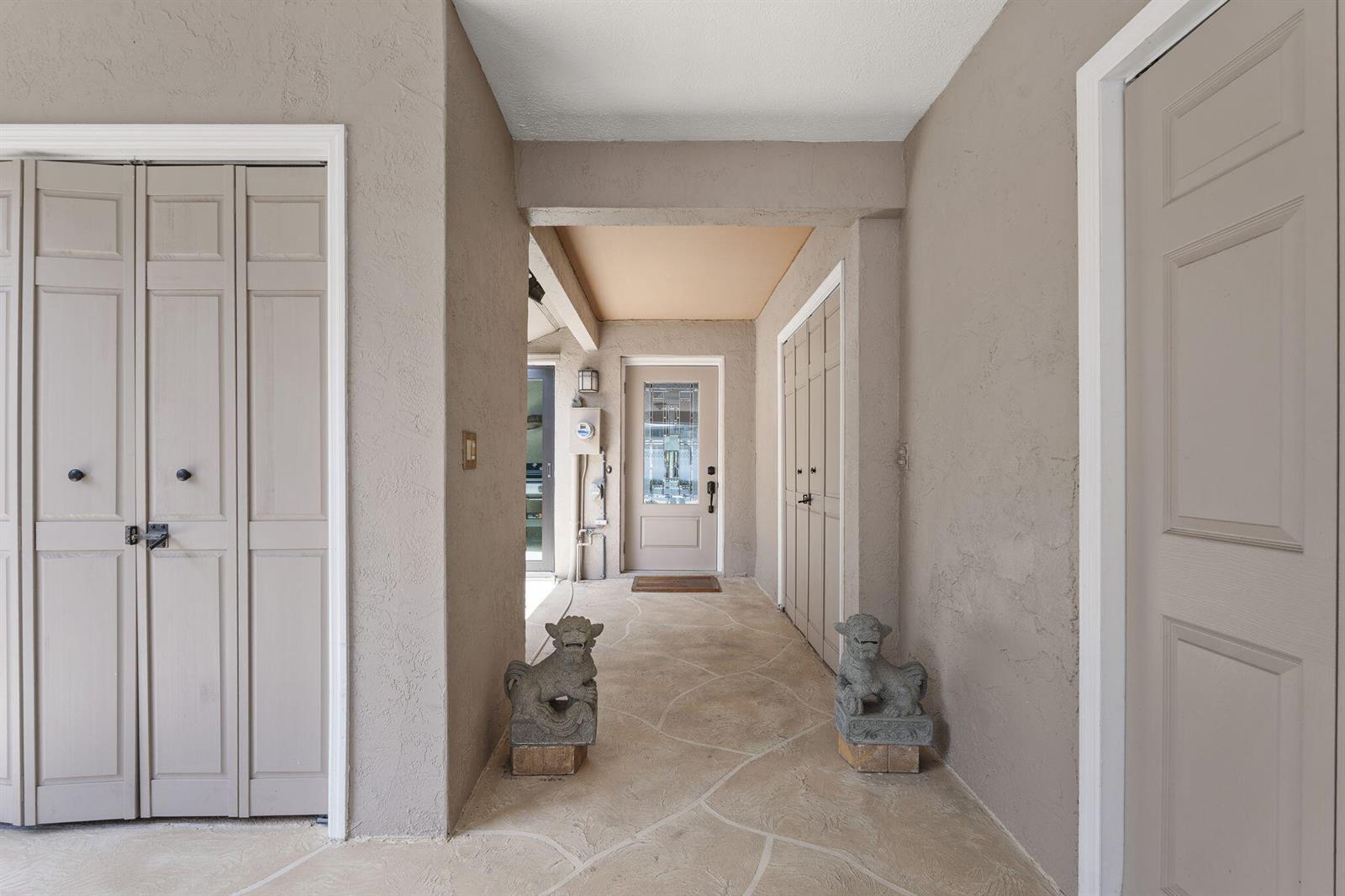 A covered entryway features stone-patterned flooring, two stone statues, and several light-colored paneled doors — 4189 SE Saint Lucie Boulevard, Stuart FL 34997, STUART, FL