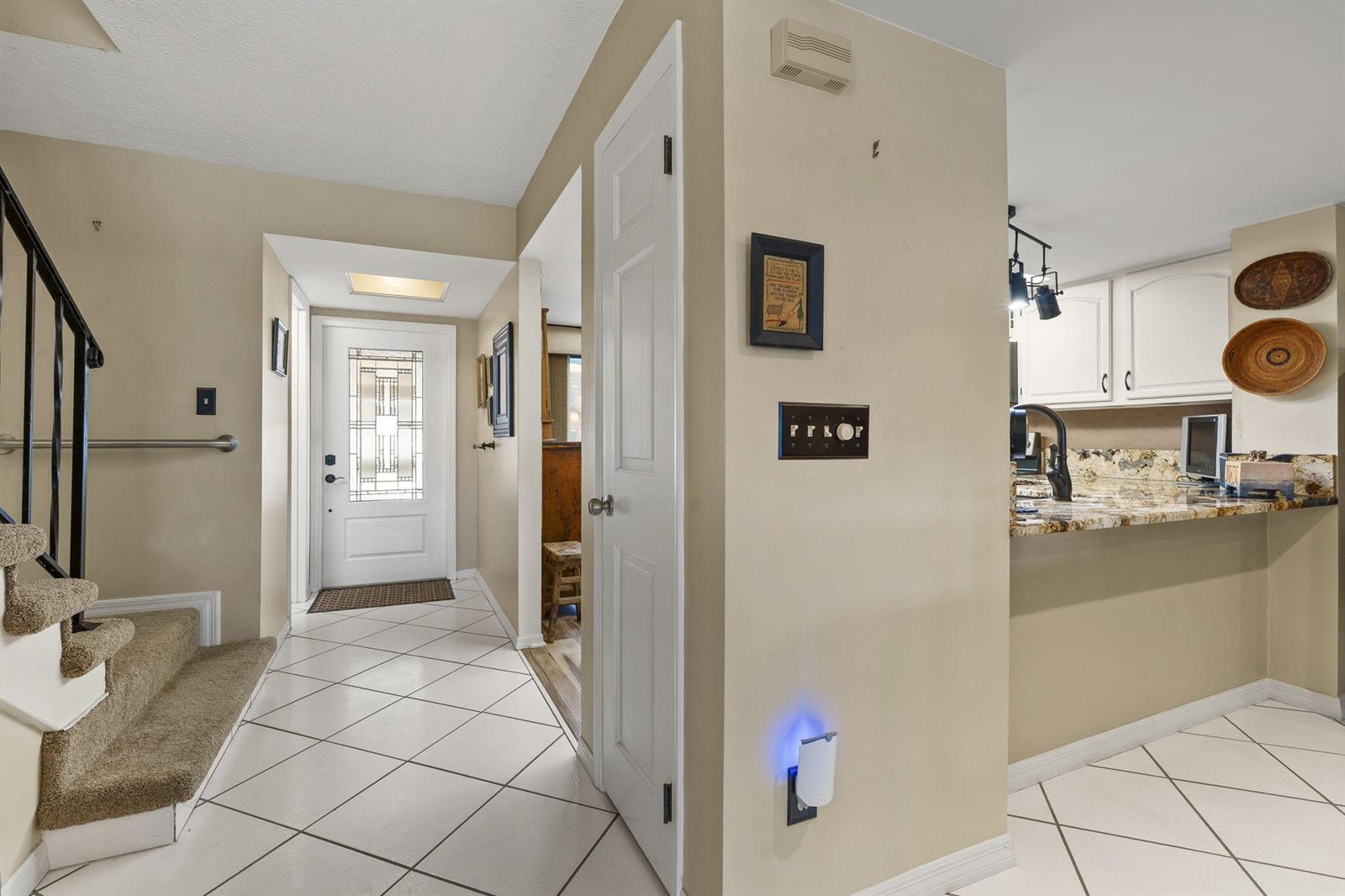 A tiled entryway features a staircase, a white front door, and an opening to a kitchen — 4189 SE Saint Lucie Boulevard, Stuart FL 34997, STUART, FL