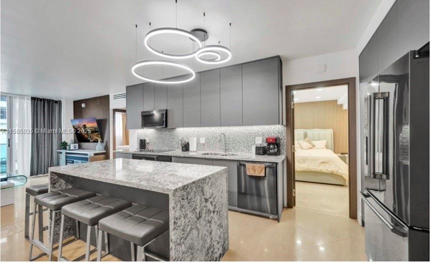 A modern kitchen features gray cabinetry, a granite-topped island with bar stools, and pendant lighting — 4001 S Ocean Dr # 3L, Hollywood FL 33019, HOLLYWOOD, FL
