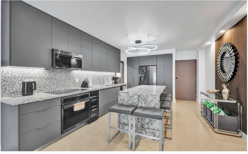 A modern kitchen features gray flat-panel cabinetry, granite countertops, a central island, and stainless appliances — 4001 S Ocean Dr # 3L, Hollywood FL 33019, HOLLYWOOD, FL