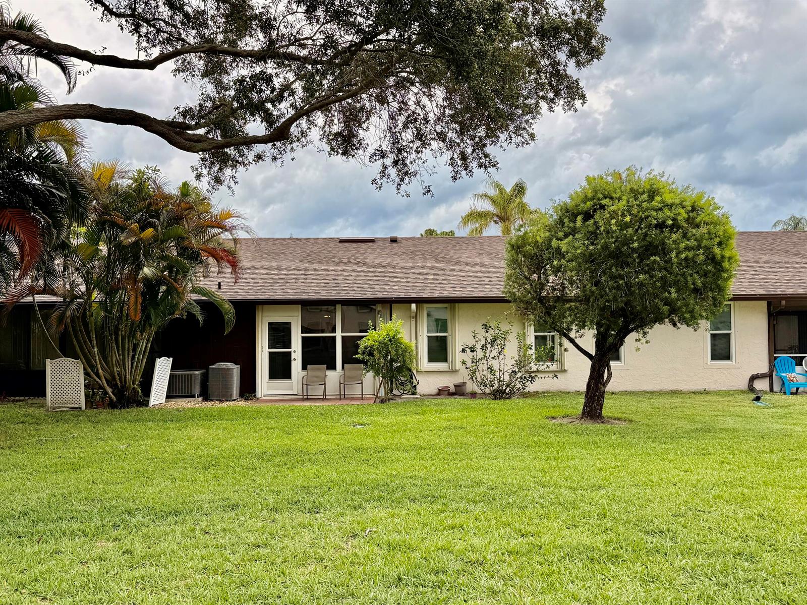 The exterior of a single-story house features a light-colored facade, a brown roof, and landscaping — 6531 SE Federal Hwy # 107, Stuart FL 34997, STUART, FL