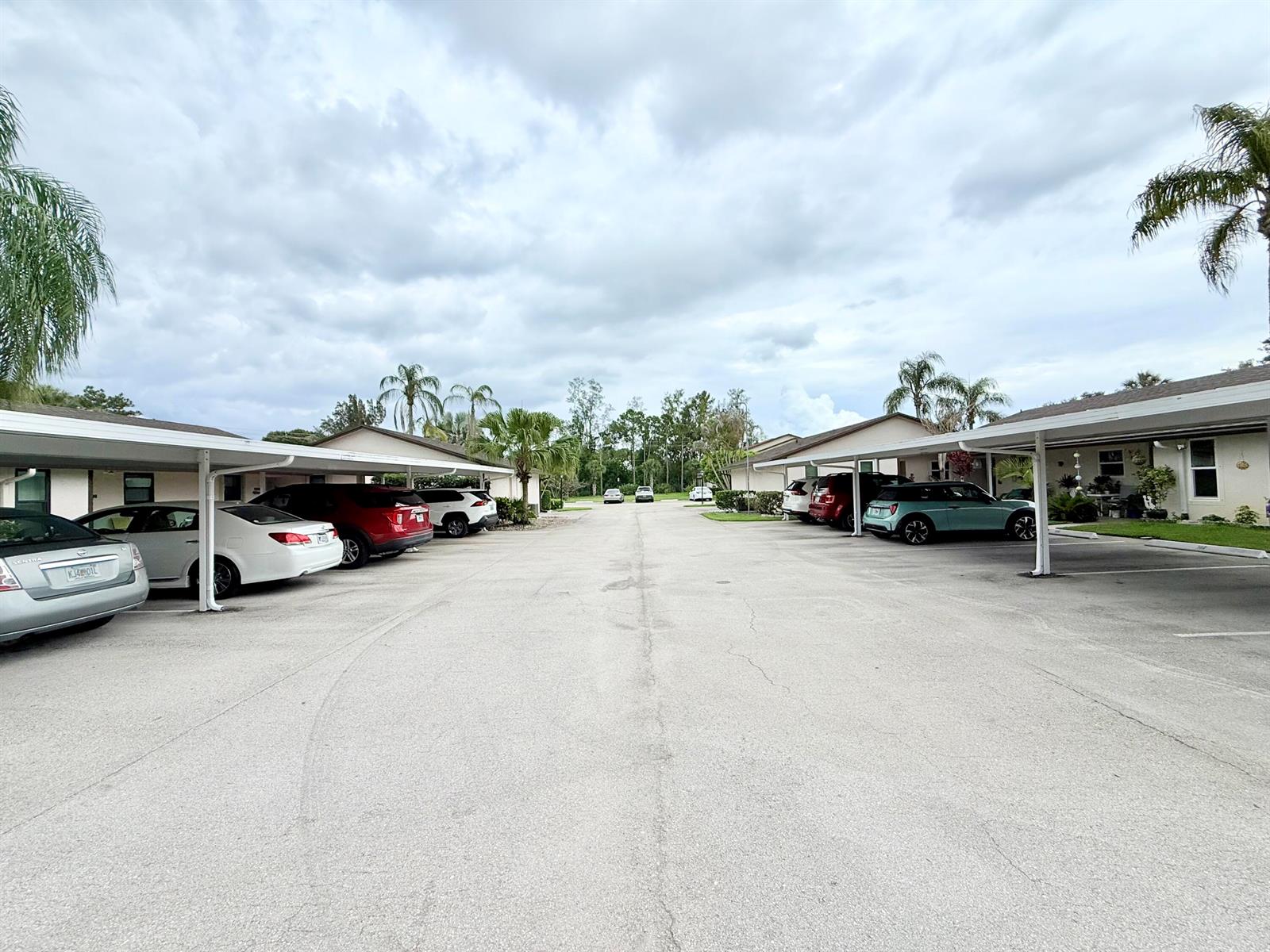 A parking lot with covered carports sits between two residential buildings under a cloudy sky — 6531 SE Federal Hwy # 107, Stuart FL 34997, STUART, FL