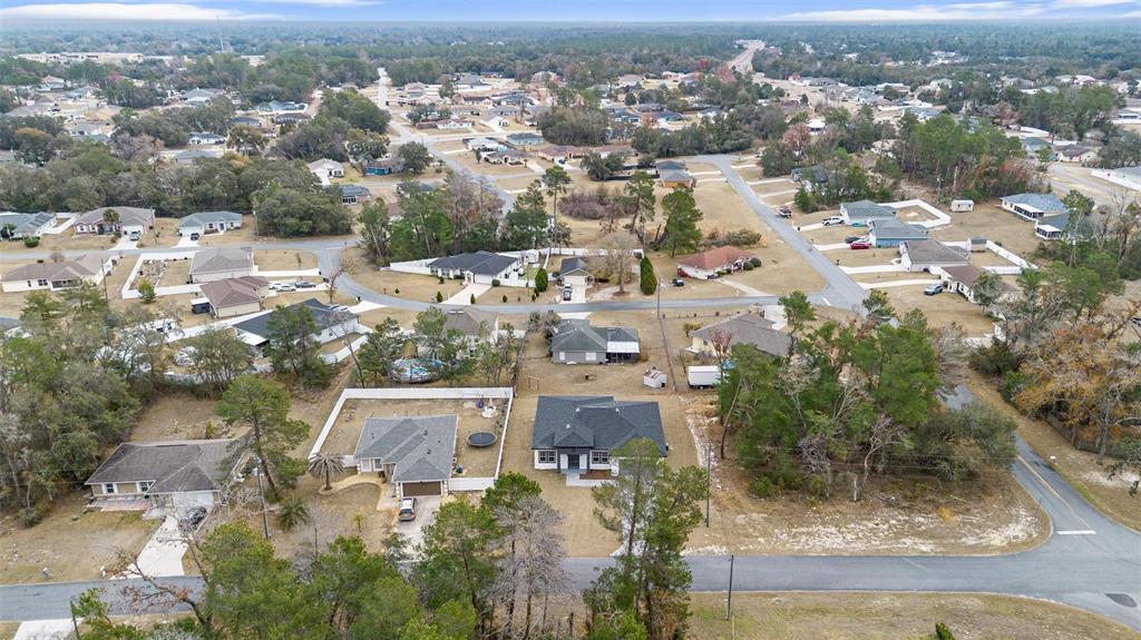An aerial view shows a suburban neighborhood with single-family homes, paved streets, and wooded areas — 15303 SW 48TH AVENUE, OCALA, FL