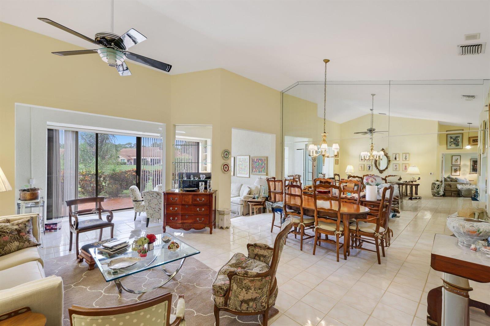 A spacious living and dining area with vaulted ceilings, tile floors, and a mirrored wall — 8423 Juddith Avenue, Boynton Beach FL 33472, BOYNTON BEACH, FL