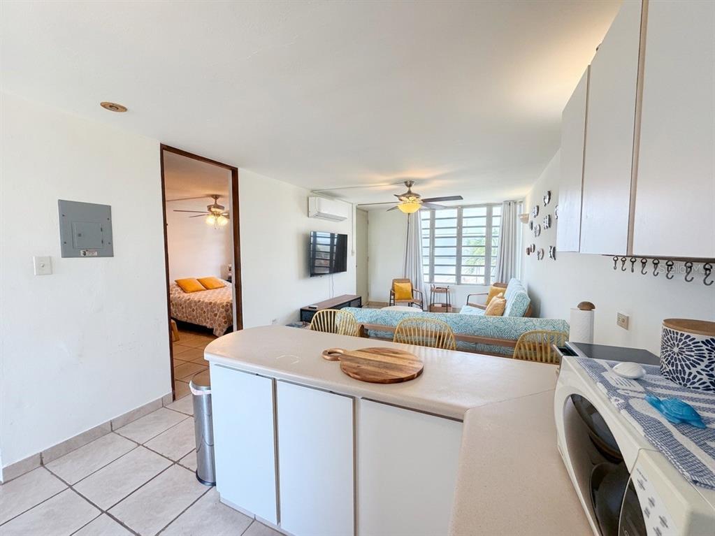 A kitchen counter overlooks a living area with a sofa and a bedroom doorway — #16 COND. PARGUERA SUITES, LAJAS, PR