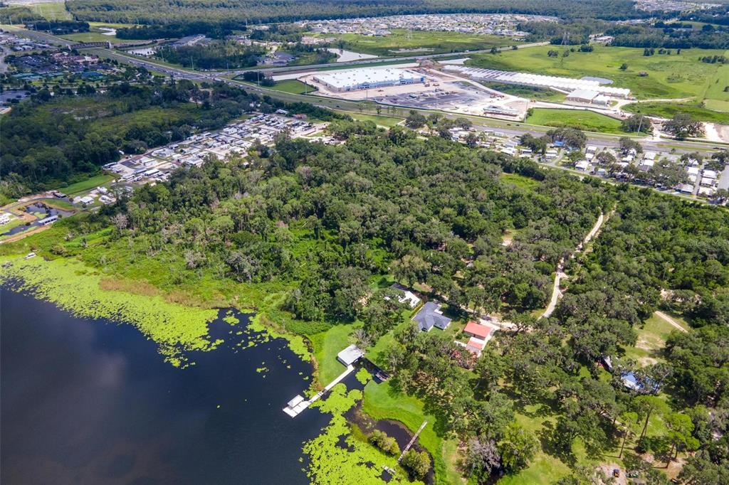 An aerial view shows a house with a dock on a lake near a forest — 7476 NE 49TH LANE, WILDWOOD, FL
