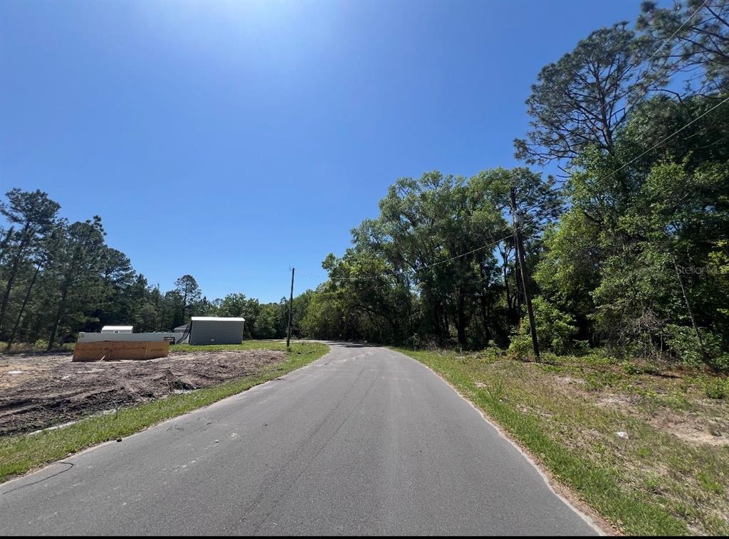 A paved road winds through a wooded area with a small building on the left — TBD LOCUST COURSE RADIAL LOT 20, OCALA, FL