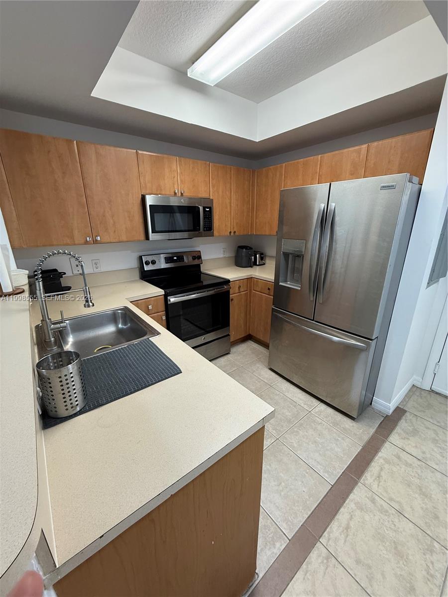 This kitchen features light wood cabinets, stainless steel appliances, and beige countertops — 119 SW 6th Ave # 405, Miami FL 33130, MIAMI, FL