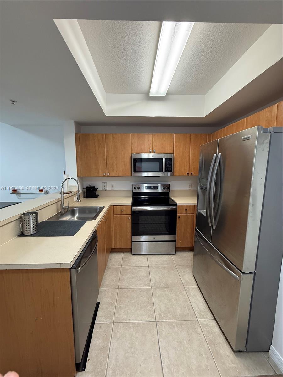A kitchen features light-colored countertops, wood cabinets, and stainless steel appliances — 119 SW 6th Ave # 405, Miami FL 33130, MIAMI, FL