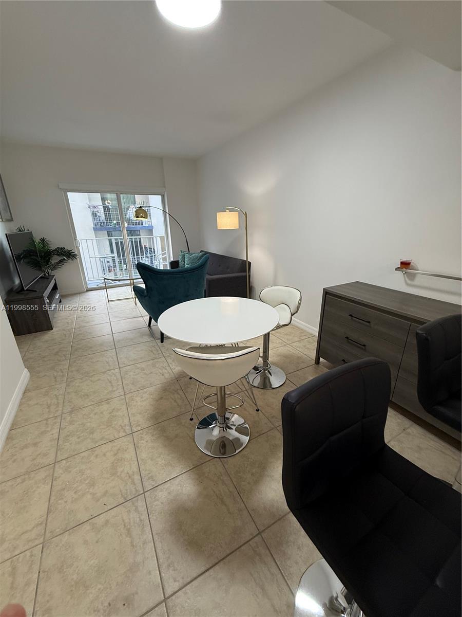 This living and dining area features tile flooring, a balcony, and modern furniture — 119 SW 6th Ave # 405, Miami FL 33130, MIAMI, FL