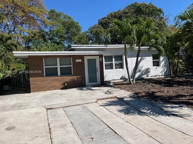 A single-story house with a white exterior, wood-paneled accent wall, and a concrete driveway — 175 NW 121st St, North Miami FL 33168, NORTH MIAMI, FL