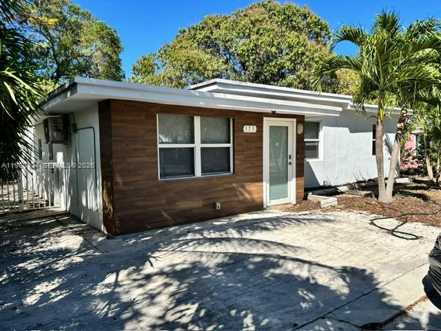 A single-story house features a wood-paneled facade, a white door, and a concrete driveway — 175 NW 121st St, North Miami FL 33168, NORTH MIAMI, FL