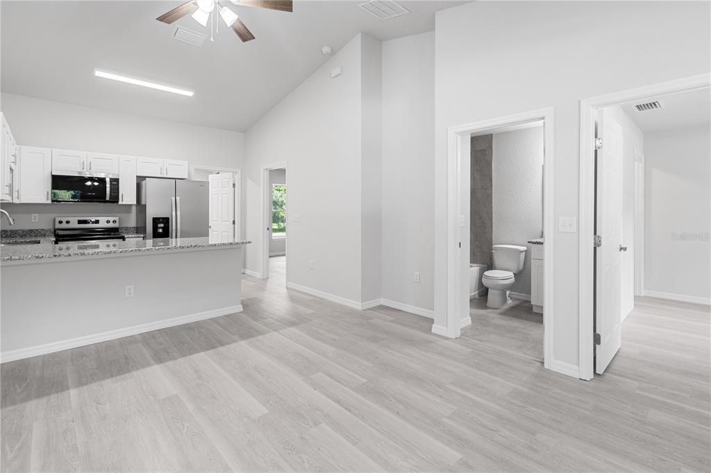 A kitchen with white cabinets and a breakfast bar opens to a hallway and bathroom — 607 SE 4TH DRIVE UNIT B, WILLISTON, FL