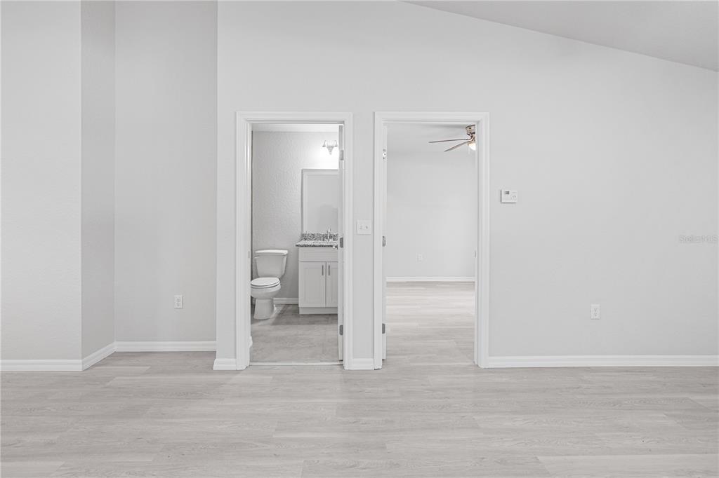 A room with light wood-look flooring features two doorways leading to a bathroom and bedroom — 607 SE 4TH DRIVE UNIT B, WILLISTON, FL