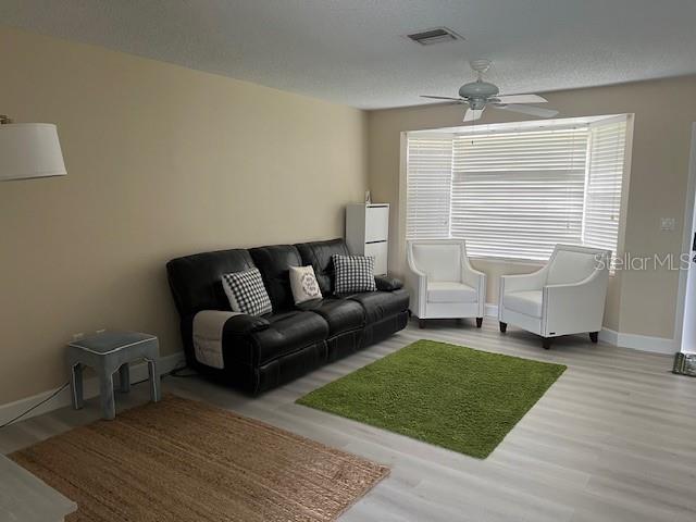 A living room features a black sofa, two white armchairs, and two rugs on light flooring — 4192 GINGOLD STREET, PORT CHARLOTTE, FL