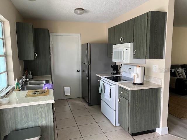 A kitchen features green wood-grain cabinets, stainless steel appliances, and light-colored tile flooring — 4192 GINGOLD STREET, PORT CHARLOTTE, FL