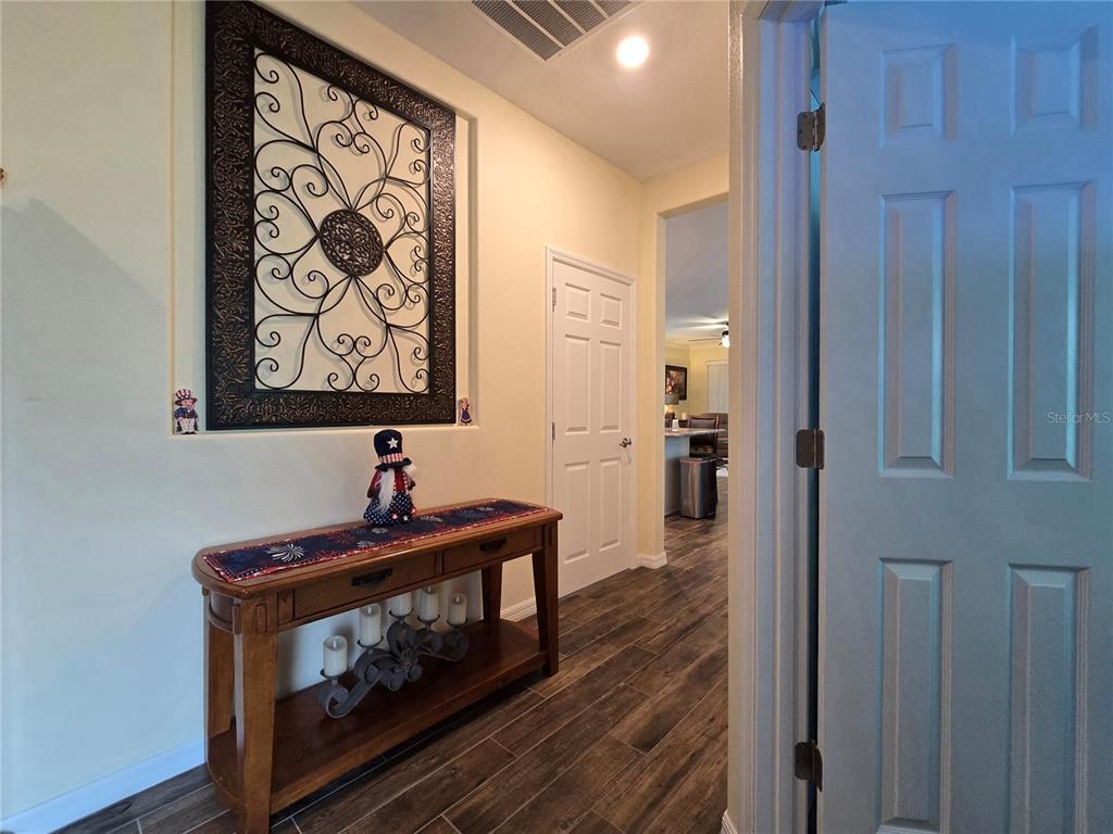 A hallway features a wooden console table, decorative wall art, and wood-look tile flooring — 373 VESTRELLA DRIVE, POINCIANA, FL