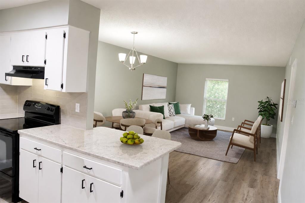 A kitchen with white cabinets and granite countertops overlooks an open-concept living and dining area — 165 PICARDY VILLA CIRCLE UNIT 201, BRANDON, FL