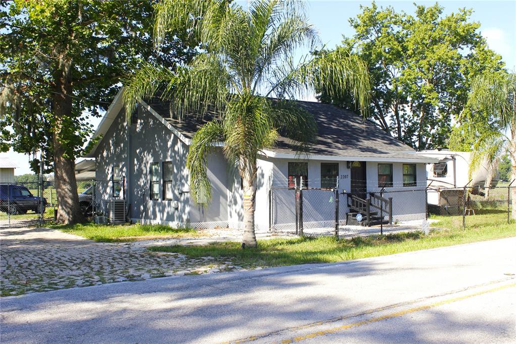 A single-story gray house with a palm tree and a chain-link fence in front — 2207 SPARKMAN ROAD, PLANT CITY, FL