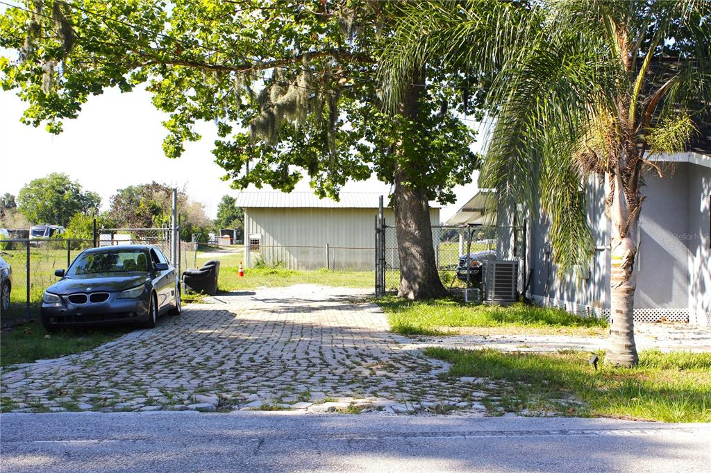 A paved driveway leads to a fenced yard with a metal shed and a parked car — 2207 SPARKMAN ROAD, PLANT CITY, FL