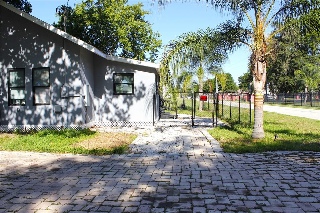 A gray house with black-framed windows sits next to a fenced yard with a palm tree — 2207 SPARKMAN ROAD, PLANT CITY, FL