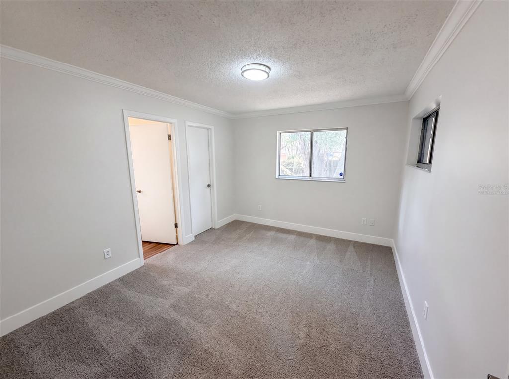 A bedroom with gray carpet, white walls, a window, and two closed doors — 2768 GALATIAN PLACE, ORLANDO, FL